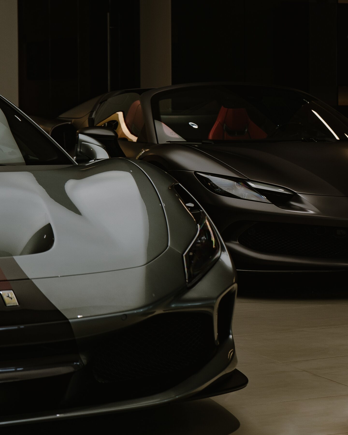 Two Ferrari sports cars photographed in a dim private collection.