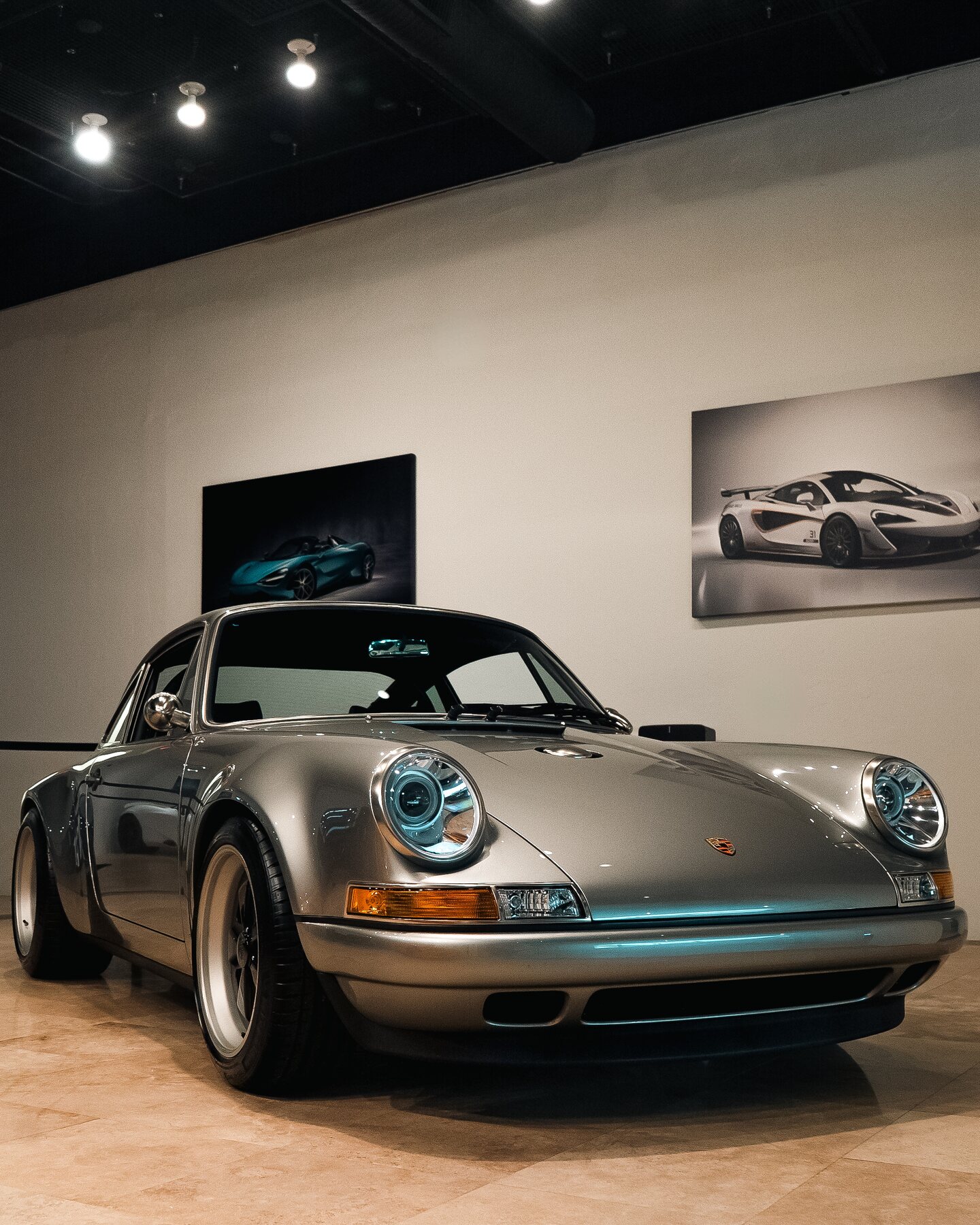 Silver Porsche 911 photographed from the front inside a private automotive gallery.