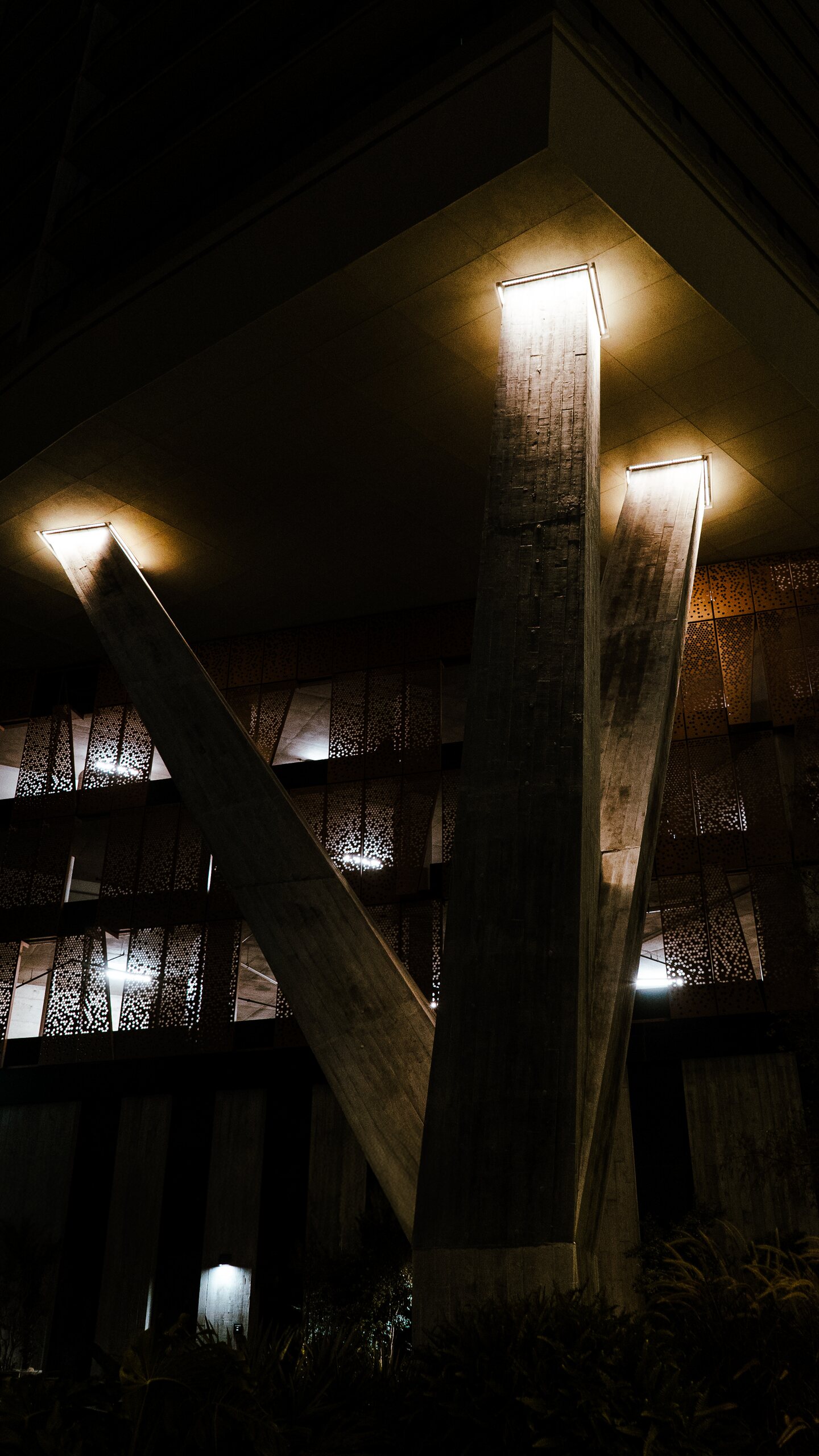 Angular concrete columns and architectural lighting photographed at night.