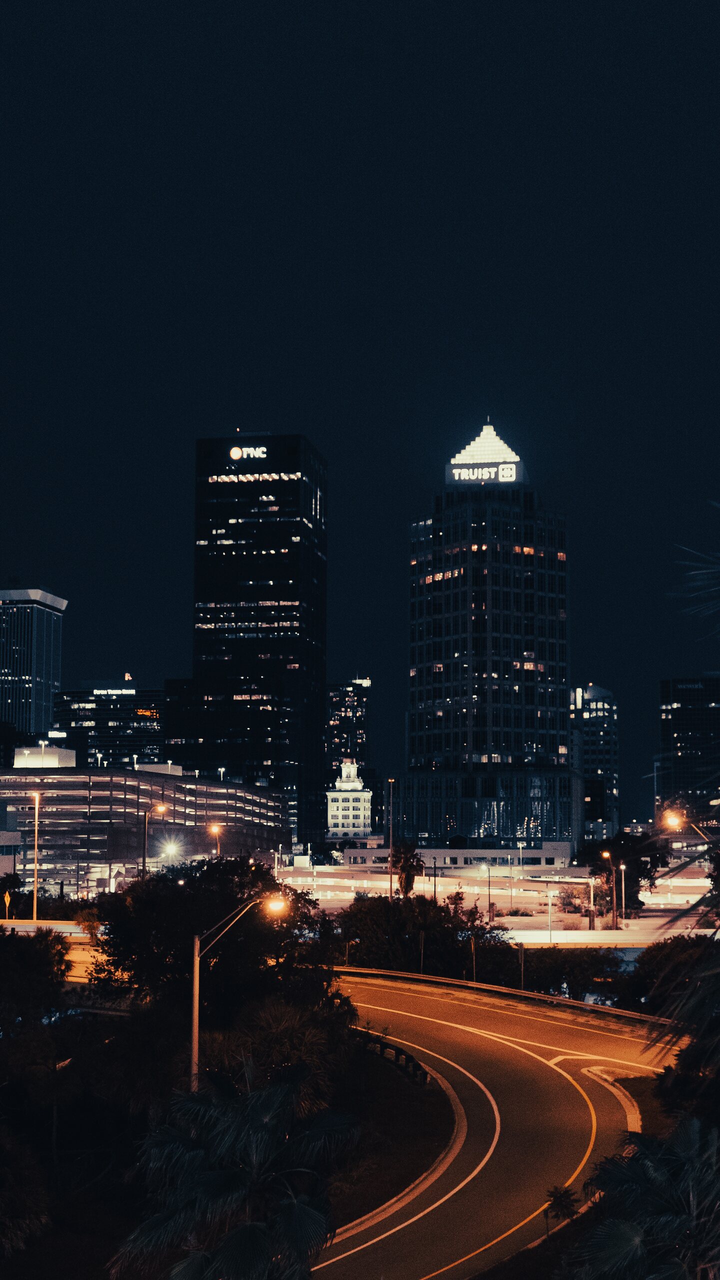 Downtown Tampa skyline and a curving roadway photographed at night.