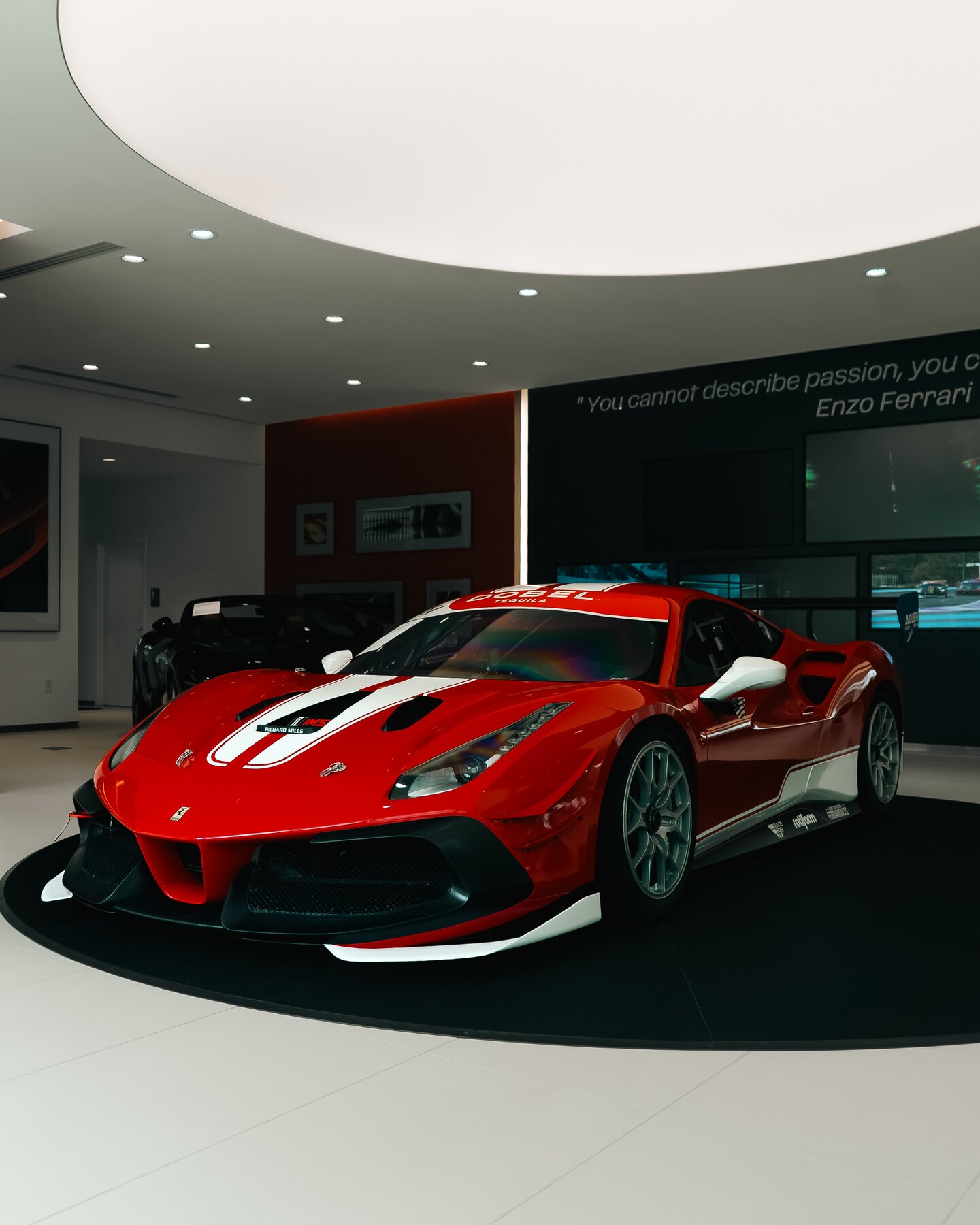 Red and white Ferrari race car photographed from the front inside the showroom.