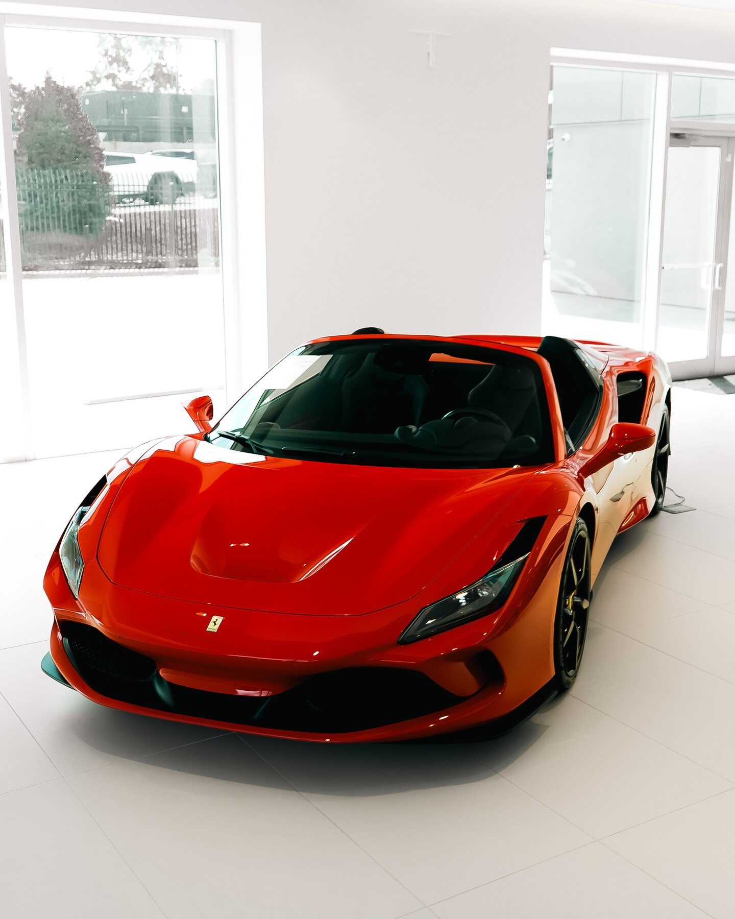 Red Ferrari photographed from the front three-quarter angle in the showroom.
