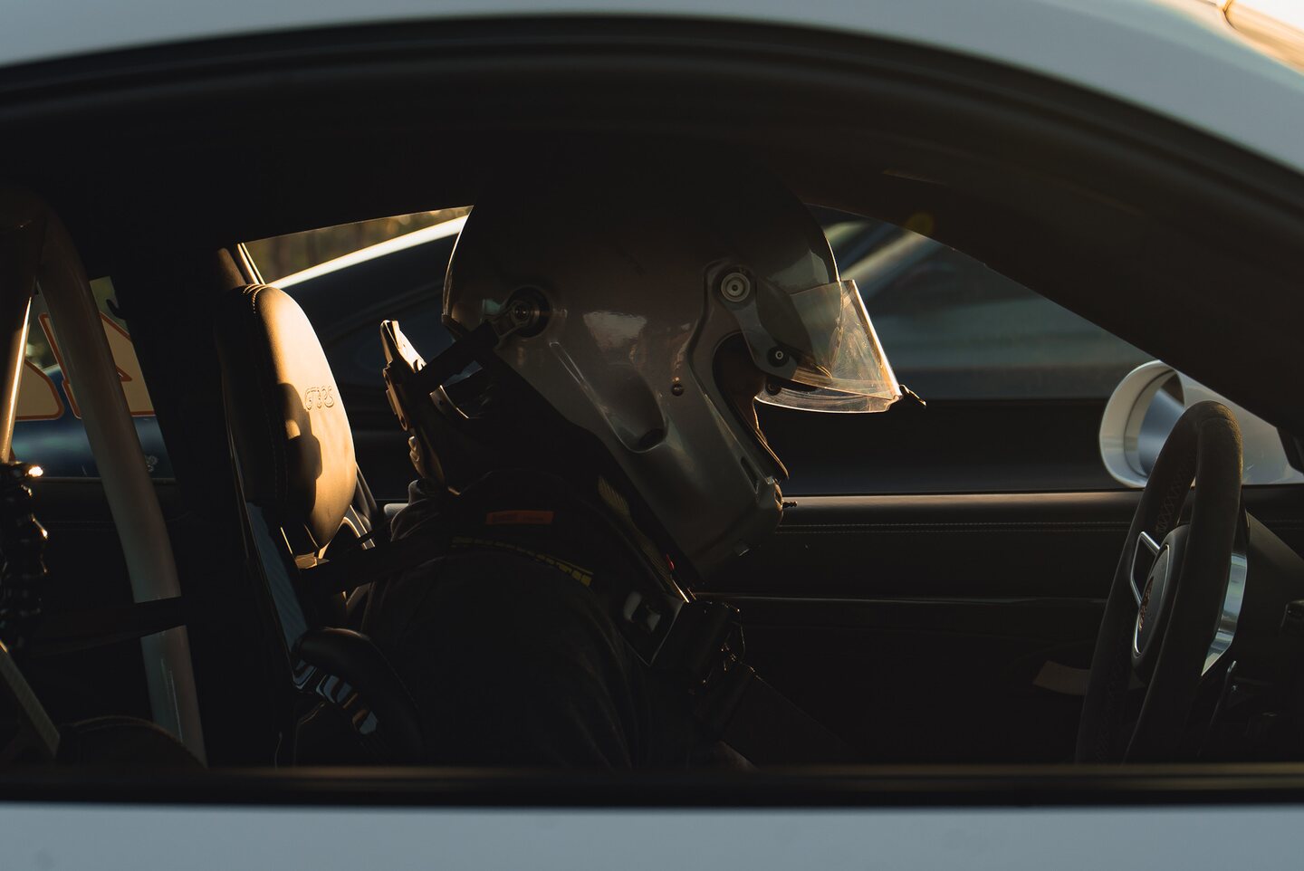 A helmeted driver seated inside a car before a track session.