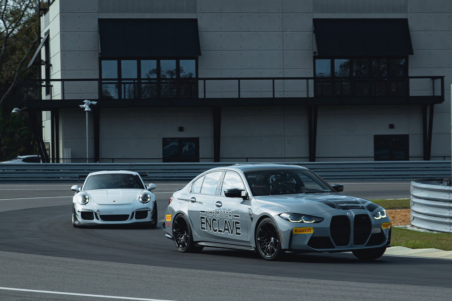A Porsche and a BMW entering a track corner together.