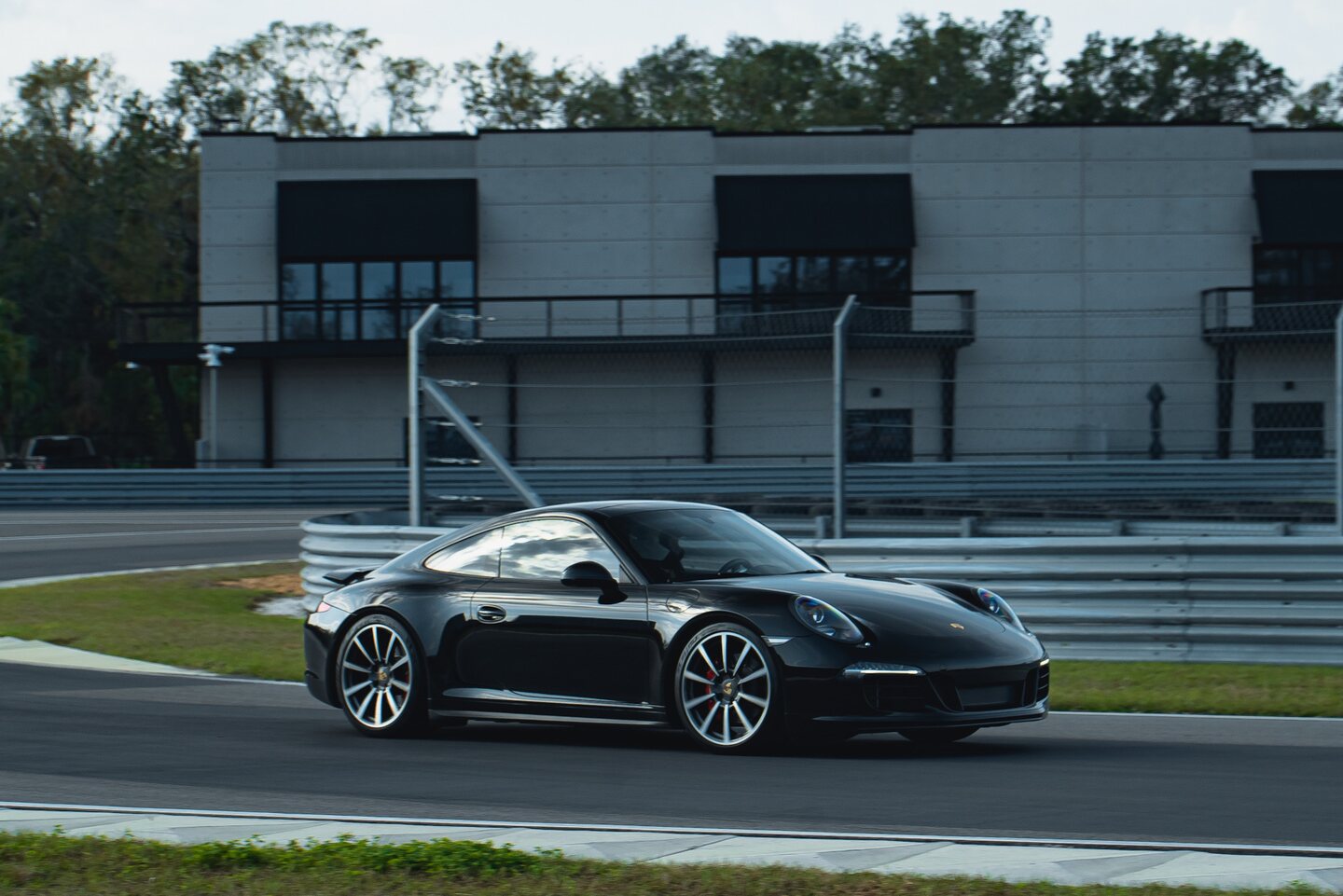 A dark Porsche driving through a corner during the track event.