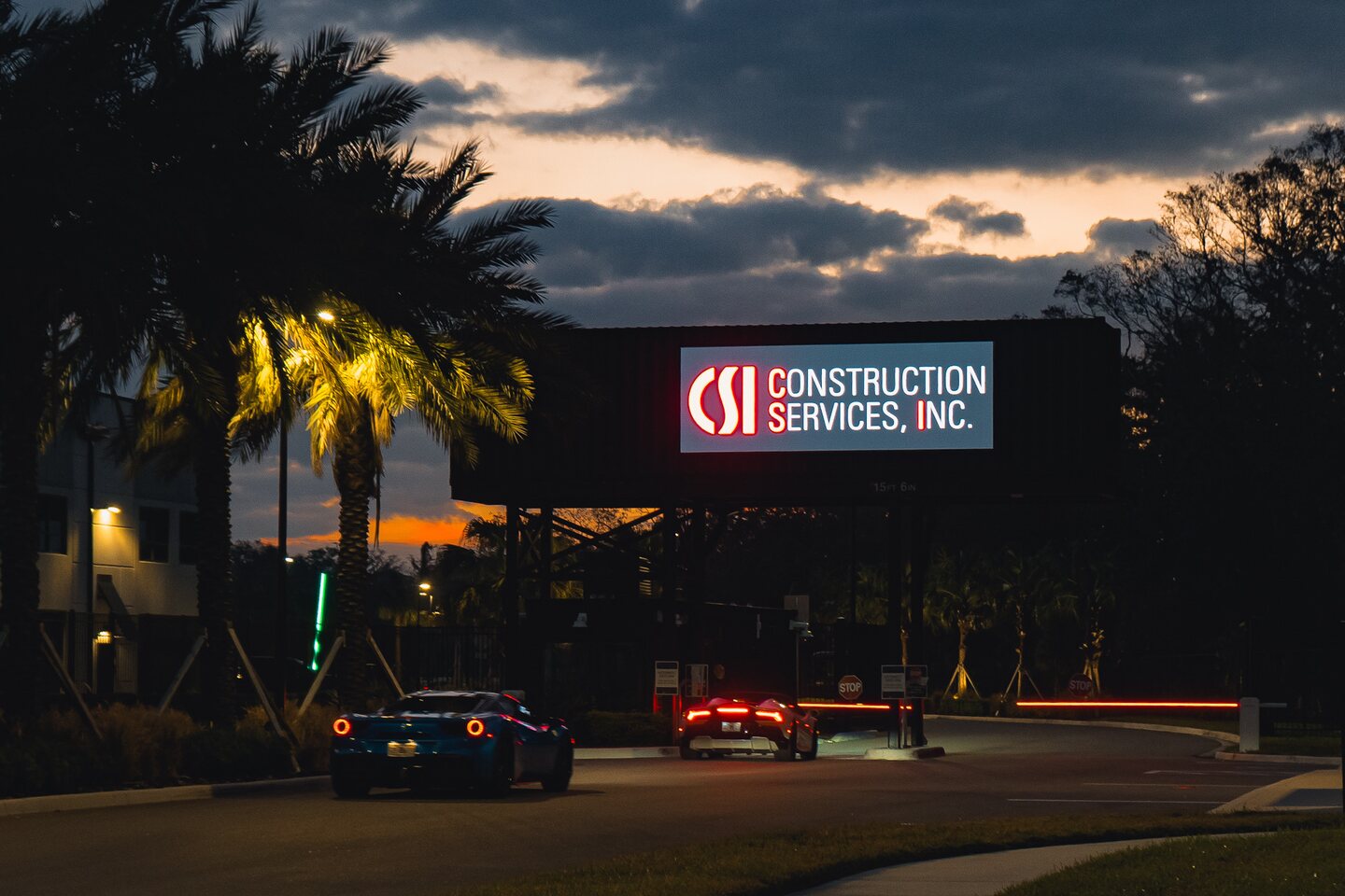 The illuminated Construction Services Inc. sign overlooking the track at dusk.