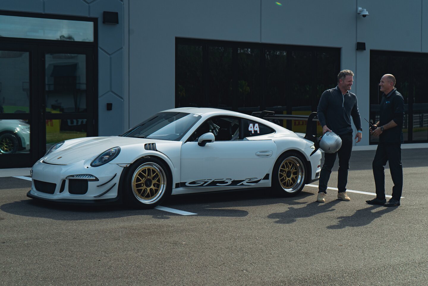 A white Porsche GT3 RS and its drivers staged beside the track.