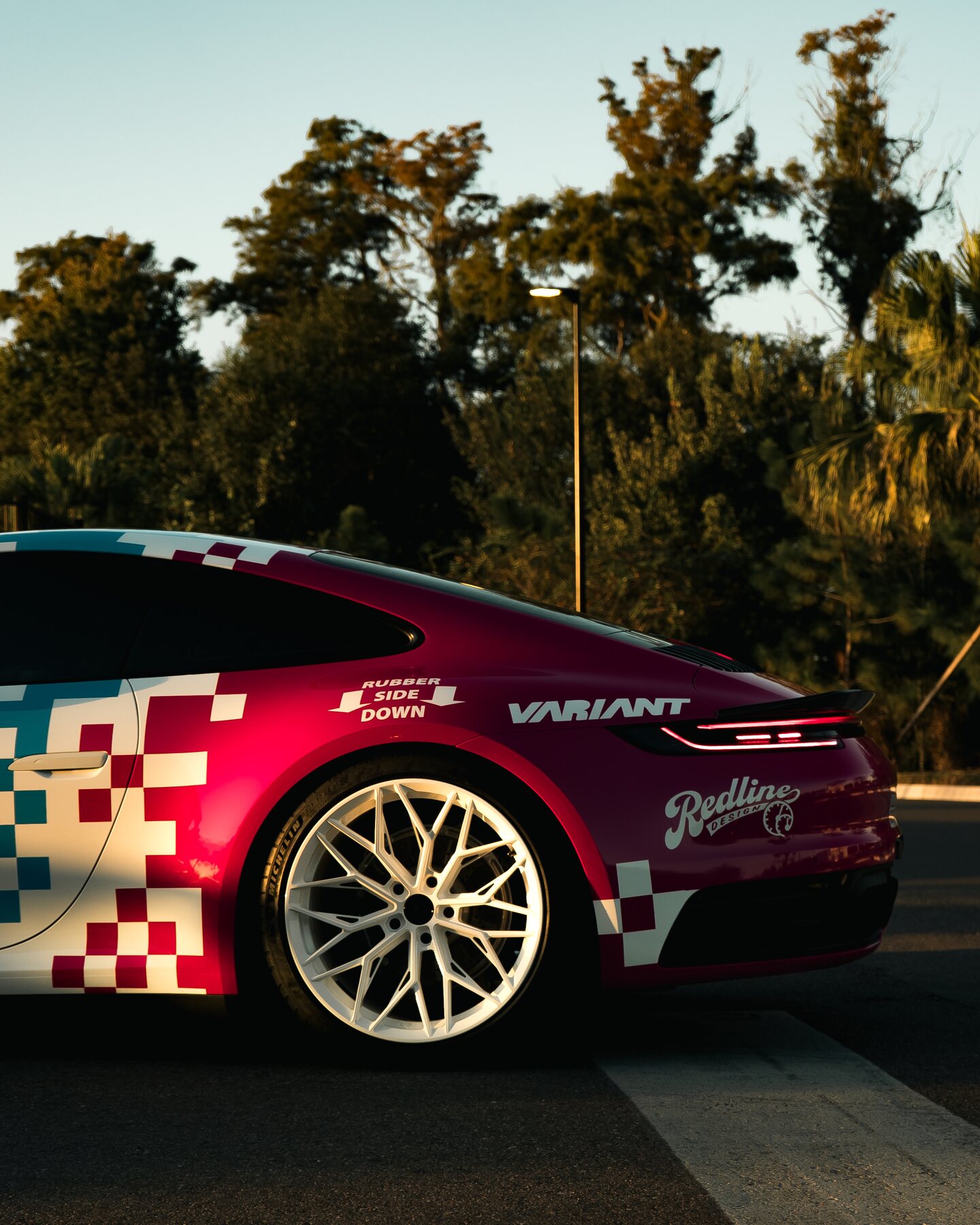A Porsche with vivid event livery photographed in warm evening light.