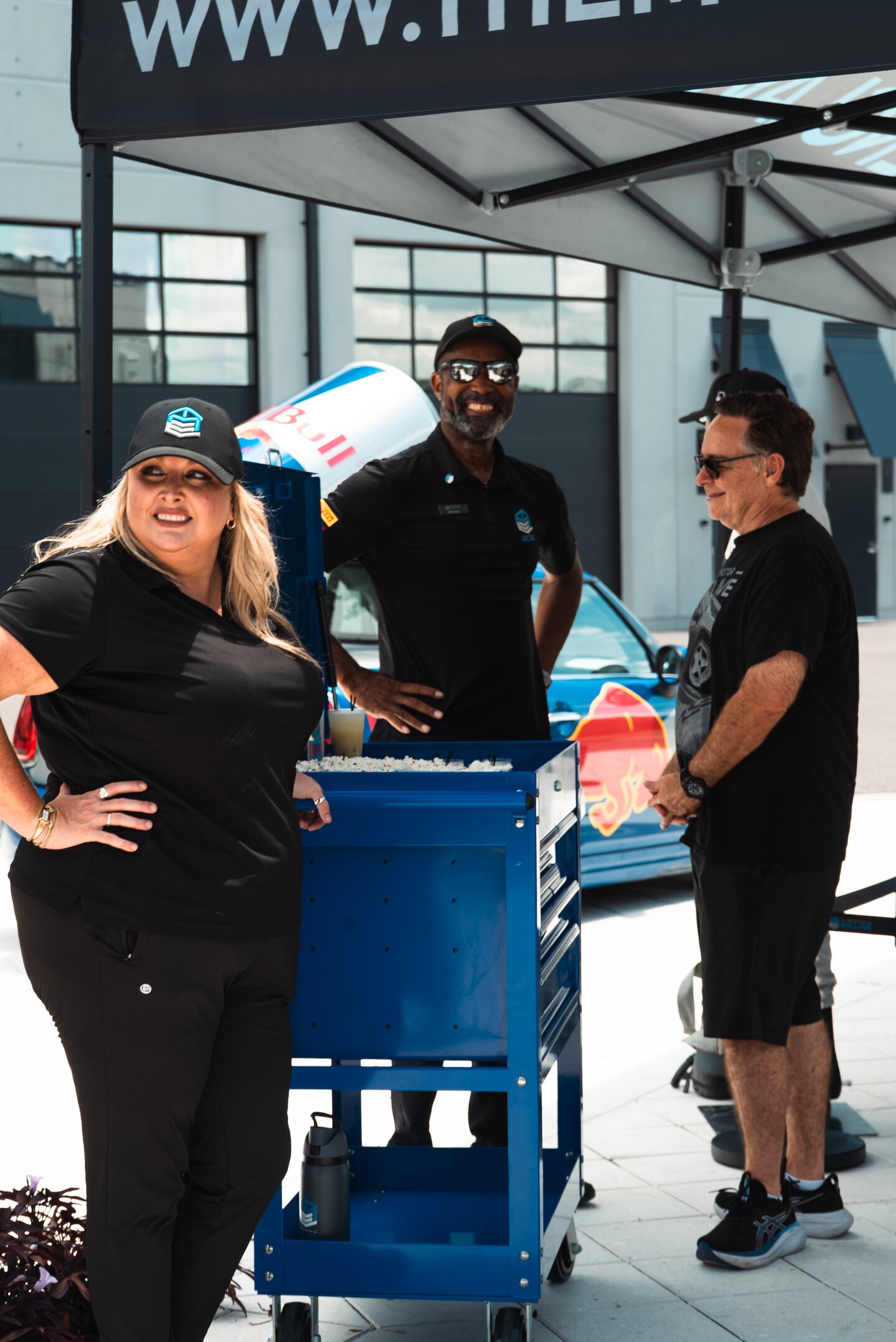 Event staff gathered beside equipment and a branded vehicle at The Motor Enclave.